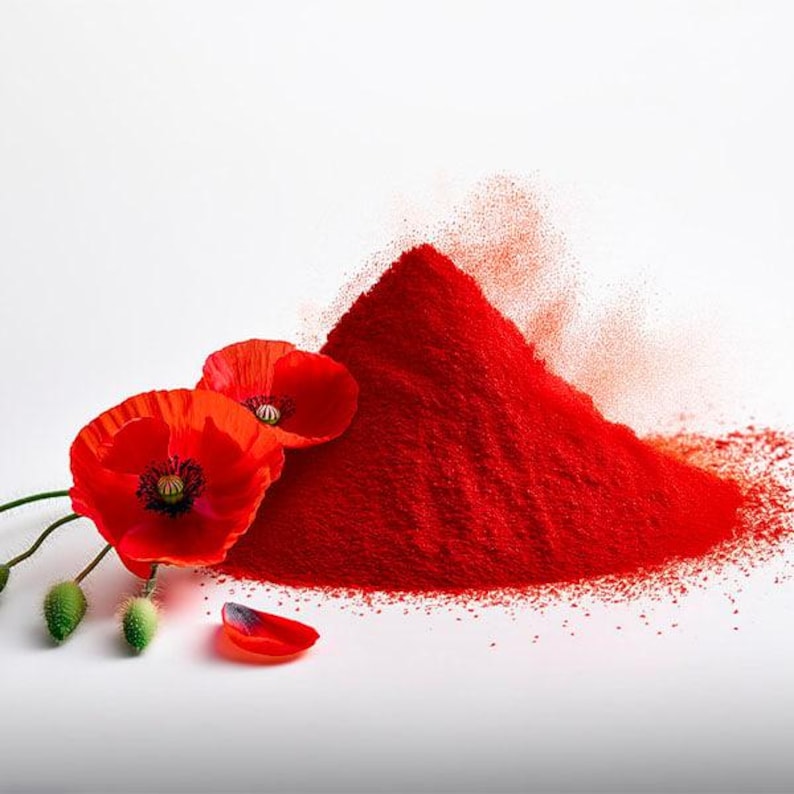 May include: A vibrant image featuring a mound of bright red powder, possibly pigment or spice, next to several red poppy flowers with dark centers. The flowers have green stems and buds, with a single petal detached.