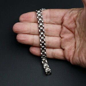 A vintage sterling silver panther style link bracelet made in Italy is displayed on a hand for scale