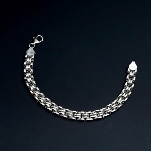 A vintage sterling silver panther style link bracelet made in Italy is displayed on a dark background
