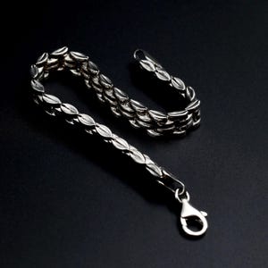 A vintage sterling silver panther style link bracelet made in Italy is displayed on a dark background this view shows the sides of the links