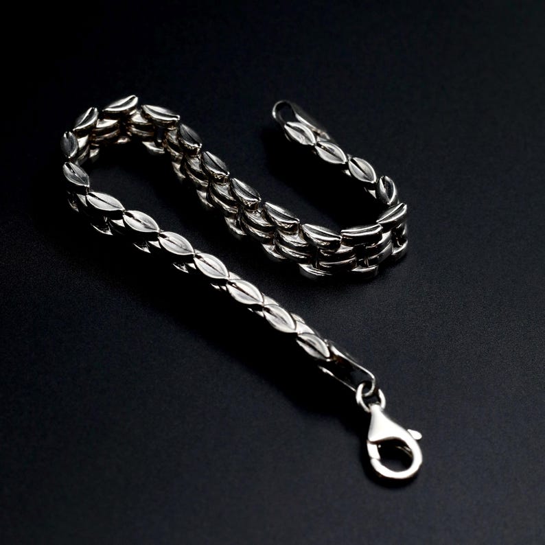 A vintage sterling silver panther style link bracelet made in Italy is displayed on a dark background this view shows the sides of the links