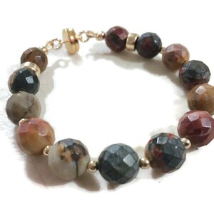 May include: A bracelet made of brown, red, and green gemstone beads with gold accents.