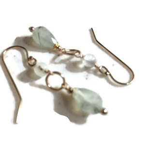 May include: A pair of gold dangle earrings with green and white gemstone beads.