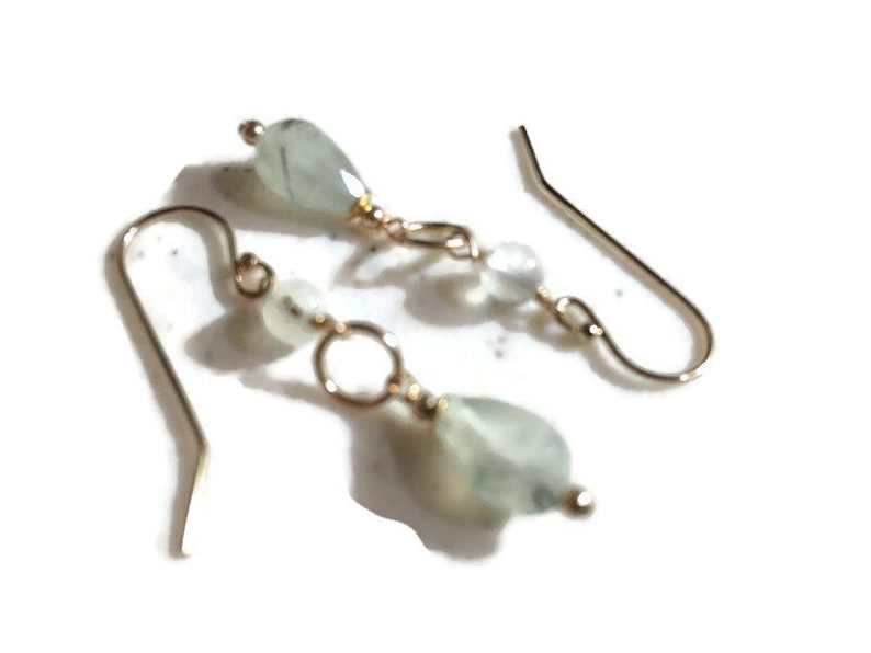 May include: A pair of gold dangle earrings with green and white gemstone beads.