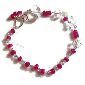 May include: A silver chain bracelet with pink gemstone beads and a clear crystal charm.