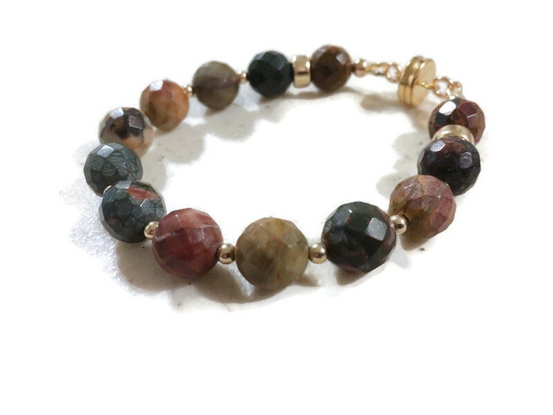 May include: A bracelet made of faceted, multi-colored gemstone beads with gold accents and a magnetic clasp.
