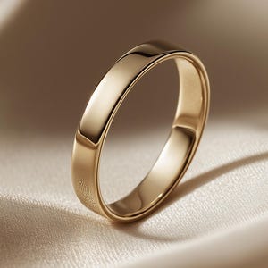 Op de afbeelding: Een gepolijste gouden ring met een glad, afgerond buitenoppervlak en een reflecterende metalen afwerking. De ring heeft een eenvoudig, doorlopend cirkelvormig ontwerp met een constante breedte over de gehele omtrek van de band.