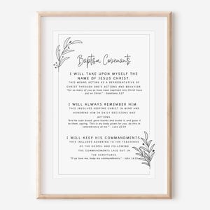 May include: A framed print with the text "Baptism Covenants" and related scripture verses. The print has a white background with black text and decorative floral elements in the corners. The frame is a light wood color.