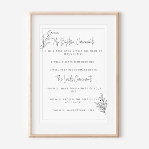 May include: A framed print with the text "My Baptism Covenants" and "The Lords Covenants" in elegant script. The text is in black on a white background, with decorative floral elements. The frame is a light wood color.