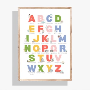 May include: A framed alphabet print with colorful letters and corresponding words like "Angel" and "Baptism." Each letter is a different color, with small illustrations. The print is in a wooden frame.