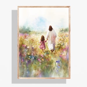 May include: Watercolor print of a person in a white robe holding hands with a child in a pink dress, walking through a field of colorful wildflowers. The artwork is framed in a light wood frame.