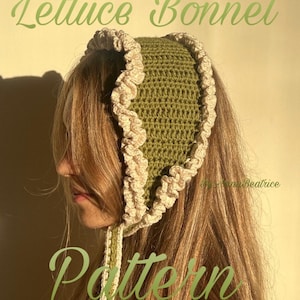 May include: A green crocheted bonnet with a ruffled edge and ties. The bonnet has the words "Lettuce Bonnet Pattern" in a light green script. The bonnet is a handmade item.