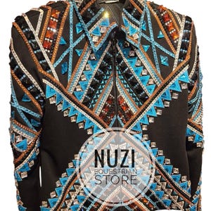 Könnte beinhalten: Schwarze Reitjacke mit aufwendigen geometrischen Mustern. Die Jacke ist mit türkisfarbenen, orangefarbenen und silbernen Strasssteinen und Pailletten verziert. Sie hat einen Reißverschluss und wird auf einem Holzbügel präsentiert. Der Text "NUZI EQUESTRIAN STORE" ist sichtbar.
