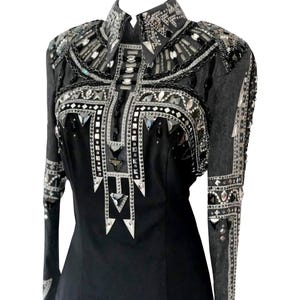 Könnte beinhalten: Schwarzes Langarmhemd mit aufwendigen silbernen und transparenten Verzierungen. Das Hemd hat einen hohen Kragen und detaillierte Muster aus Strasssteinen und verspiegelten Akzenten auf Schultern, Brust und Ärmeln. Das Design ist symmetrisch und auffällig.