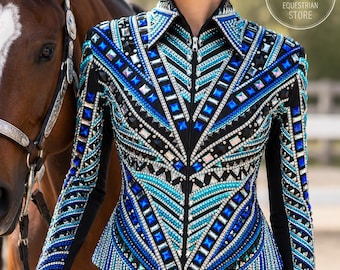 May include: A black long-sleeved equestrian show shirt featuring a front zipper, adorned with intricate geometric patterns of blue, turquoise, and clear crystals. The shirt includes a black collar and a NUZI EQUESTRIAN STORE logo.
