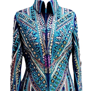 Könnte beinhalten: Aufwendig verzierte Jacke in Blau-, Türkis- und Silbertönen. Sie hat einen hohen Kragen und einen durchgehenden Reißverschluss. Das Design integriert geometrische Muster und ist mit glitzernden Edelsteinen und Perlen verziert.