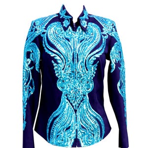 Puede incluir: Una camisa azul marino de manga larga con cuello alto y cierre de cremallera. La camisa está adornada con intrincados diseños de lentejuelas turquesas en la parte delantera, los hombros y las mangas, creando un efecto brillante. El diseño es simétrico y ornamentado.