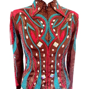 May include: A brown equestrian show jacket with a high collar and long sleeves. The jacket is decorated with turquoise, red, and clear rhinestones in a decorative pattern. The jacket has a zip closure and fringe detail on the sleeves.