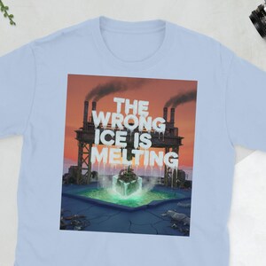 Puede incluir: Camiseta azul claro con un gráfico que dice "THE WRONG ICE IS MELTING". El gráfico muestra una fábrica con chimeneas humeantes y un cubo de hielo derritiéndose. La camiseta está hecha de un tejido suave.
