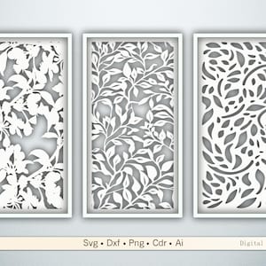 May include: Three white framed wall art panels with intricate cut-out floral and leaf designs. The panels are rectangular and feature different patterns of flowers and foliage. The background is a light gray color.