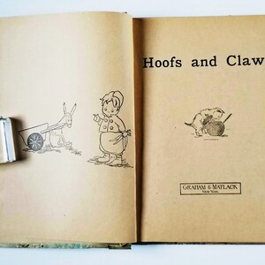 May include: An open book with the title "Hoofs and Claws" on the cover. The book features illustrations of a child with a donkey and a child with a puppy.