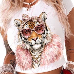 Könnte beinhalten: Ein weißes T-Shirt mit einer grafischen Illustration eines Tigers, der eine rosa Katzenaugen-Sonnenbrille, eine passende rosa Schleife, eine rosa Federboa, eine Perlenkette, eine Goldkette mit Herzanhänger und baumelnde rosa Ohrringe trägt.