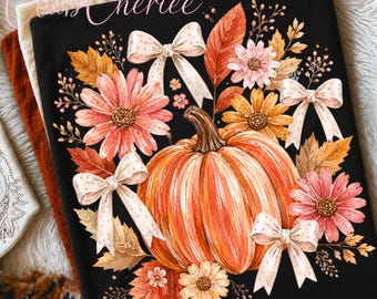 May include: A black fabric item featuring a central orange pumpkin surrounded by pink and yellow flowers, autumn leaves, and light-colored bows with small dots. The text "Club Cheriee" is printed in a cursive script in the upper left corner.