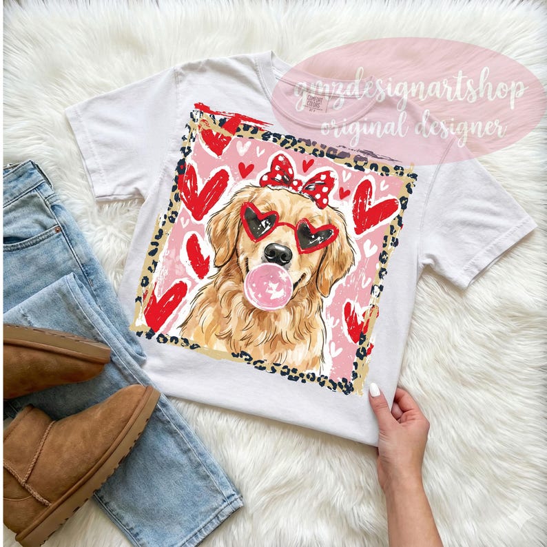 May include: White t-shirt featuring a golden retriever wearing heart-shaped sunglasses and a bow, blowing a bubblegum bubble. The design includes red hearts and a leopard print border. The text "yamzdesignartshop original designer" is visible.