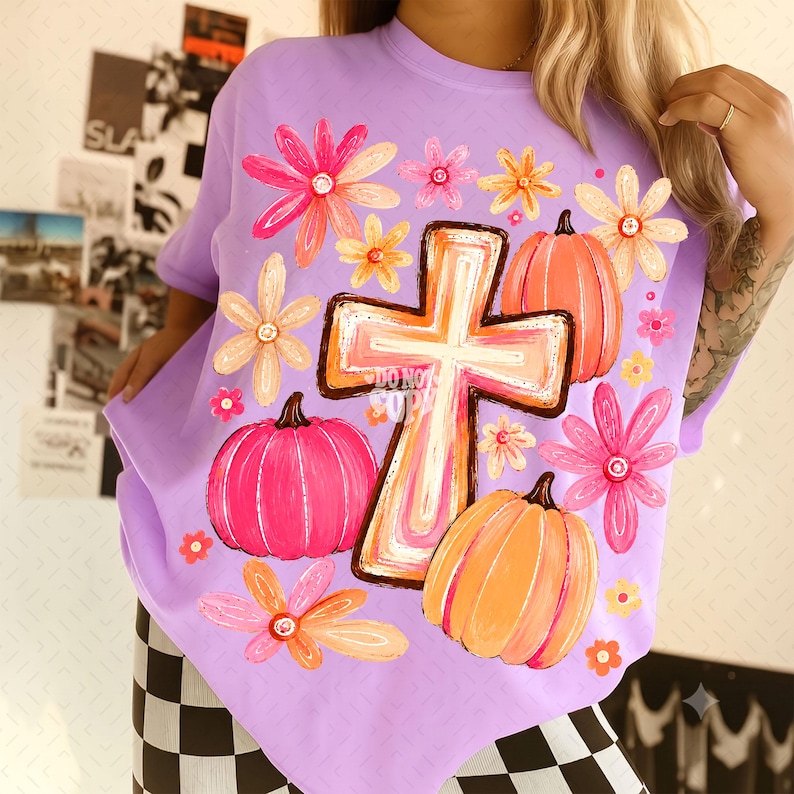 May include: A light purple t-shirt featuring a central graphic of a cross surrounded by orange and pink pumpkins and various colorful flowers. The design includes a watermark text that reads DO NOT COPY across the center of the cross graphic.
