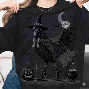 May include: A black t-shirt featuring a graphic of a black rooster wearing a witch hat, a spiderweb cape, and high-heeled boots. The design includes a jack-o'-lantern, a bubbling cauldron, a crescent moon, bats, and the text DO NOT COPY.