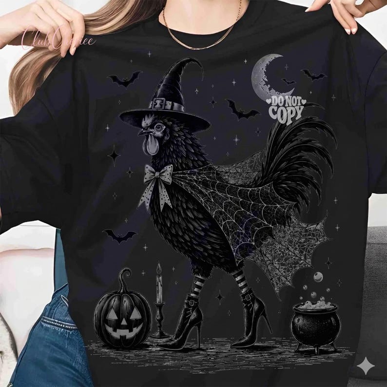 May include: A black t-shirt featuring a graphic of a black rooster wearing a witch hat, a spiderweb cape, and high-heeled boots. The design includes a jack-o'-lantern, a bubbling cauldron, a crescent moon, bats, and the text DO NOT COPY.