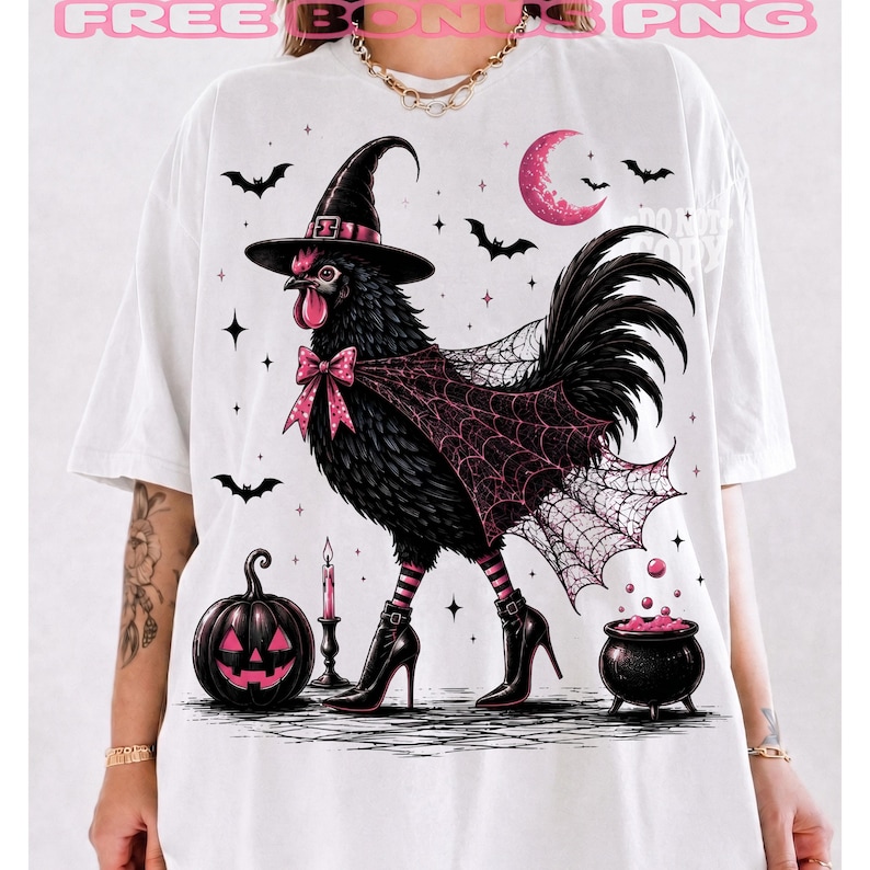 May include: A white t-shirt featuring a graphic of a black chicken wearing a witch hat, a pink bow, and black high-heeled boots. The chicken is draped in a spiderweb cape. The design includes a jack-o'-lantern, a candle, a cauldron, and bats.