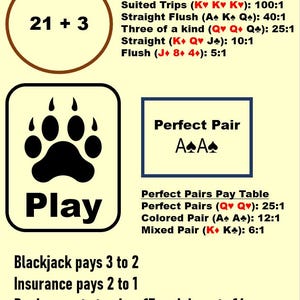 May include: A blackjack game guide with text and graphics. The top of the image reads "ULTIMATE BLACKJACK". The guide includes pay tables for "21 + 3" and "Perfect Pair" side bets, with payouts listed. A paw print graphic is labeled "Play".
