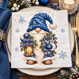 May include: A square paper napkin featuring a gnome illustration with a blue knit hat, a long white beard, and brown boots. The gnome holds a lit lantern and a bouquet of pine branches, blue ornaments, and snowflakes on a white background.