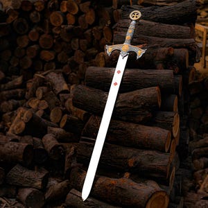 May include: A decorative sword with a silver blade and ornate gold and silver hilt. The blade has three red crosses. The sword is leaning against a stack of brown logs, creating a rustic and historical aesthetic.