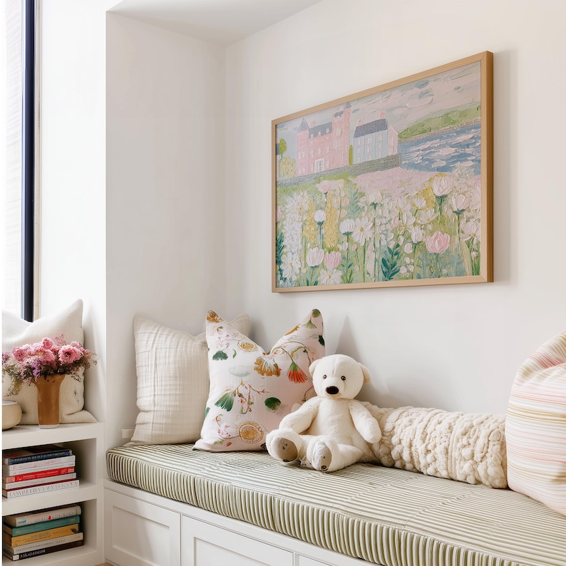 May include: A cozy window seat with a green and white striped cushion, adorned with decorative pillows and a teddy bear. A framed painting of a pink building and flowers hangs above. A shelf displays books and a vase of pink flowers.
