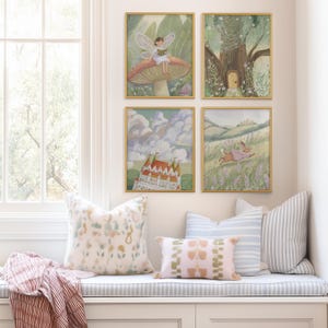 May include: Four framed art prints with gold frames, depicting whimsical scenes of a fairy, a tree with a door, a castle, and a rabbit. The prints are displayed above a window seat with decorative pillows in pastel colors.