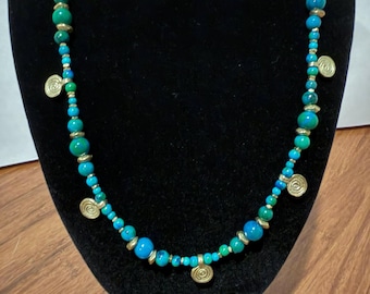 May include: A beaded necklace featuring alternating turquoise and emerald green spherical beads of varying sizes, interspersed with small metallic gold-toned spacers and several flat, circular gold-toned charms with a spiral design.
