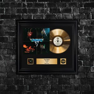 Puede incluir: Disco de oro enmarcado del álbum debut de Van Halen, con el logotipo de la banda y la portada del álbum. El marco incluye un disco de oro, imágenes de la portada del álbum y una placa con el nombre de la banda y detalles del álbum.
