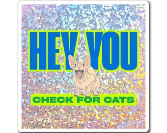 May include: A sticker with a holographic background and a cartoon Sphynx cat. The text "HEY YOU" is in blue, and "CHECK FOR CATS" is in green. The cat is beige with its mouth open.