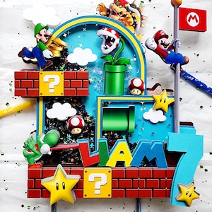 May include: A colorful cake topper featuring characters from the Super Mario Bros. video game. The design includes Mario, Luigi, Bowser, Yoshi, and other iconic elements like question mark blocks, stars, and a flag. The name "Liam" and the number "7" are also incorporated.