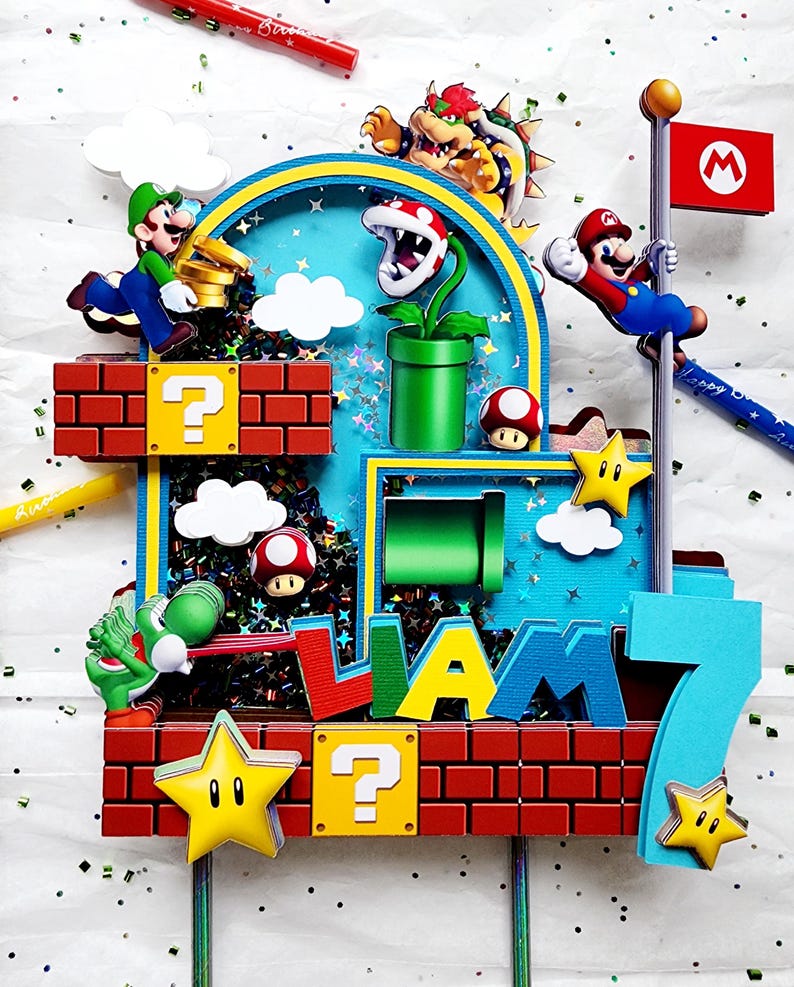May include: A colorful cake topper featuring characters from the Super Mario Bros. video game. The design includes Mario, Luigi, Bowser, Yoshi, and other iconic elements like question mark blocks, stars, and a flag. The name "Liam" and the number "7" are also incorporated.