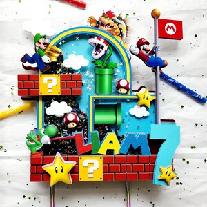 May include: A colorful Super Mario-themed cake topper featuring characters like Mario, Luigi, and Bowser. The topper includes brick blocks, question mark boxes, stars, and the name "Liam" with the number "7". Includes a red candle with "Happy Birthday" text.