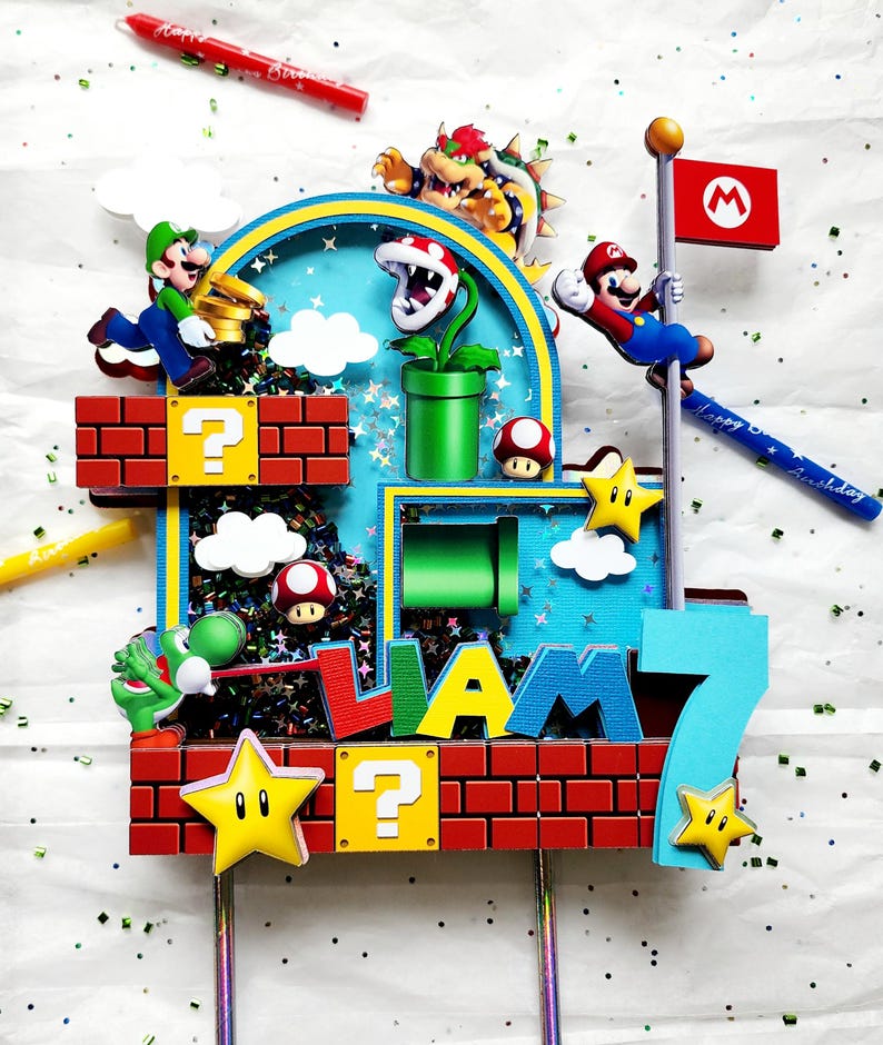 May include: A colorful Super Mario-themed cake topper featuring characters like Mario, Luigi, and Bowser. The topper includes brick blocks, question mark boxes, stars, and the name "Liam" with the number "7". Includes a red candle with "Happy Birthday" text.