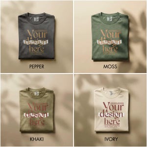 May include: Four folded t-shirts in pepper, moss, khaki, and ivory colors. Each shirt features the text "Your design here" in a stylized font. The shirts are displayed on a neutral background, showcasing the design.