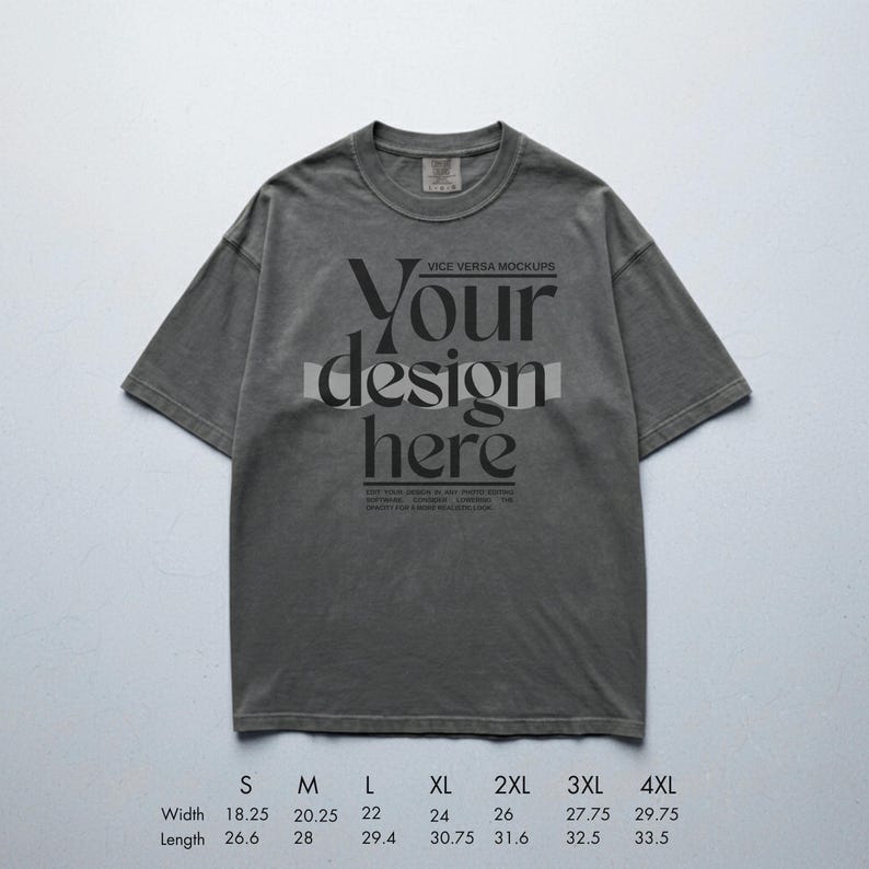 May include: A gray t-shirt with the text "Your design here" in a bold, stylized font. The shirt has a crew neck and short sleeves. Measurements are provided for various sizes, with widths ranging from 18.25 to 29.75 inches and lengths from 26.6 to 33.5 inches.