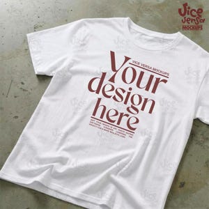 以下が含まれることがあります： 白のTシャツ。バーガンディ色の「Your design here」の文字がプリントされています。Tシャツは少しシワがあり、柔らかい素材のようです。「Vice Versa Mockups」の文字も確認できます。