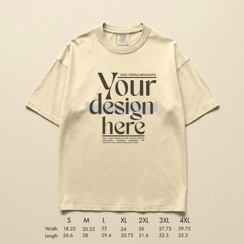 May include: Cream-colored t-shirt with the text "Your design here" in a bold, black font. The shirt has a crew neck and short sleeves. Size chart with width and length measurements in inches is at the bottom.