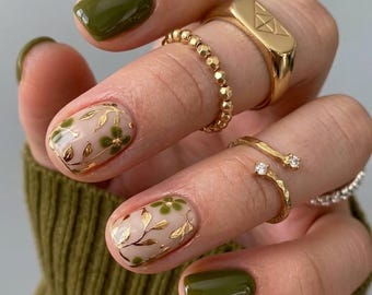 Elegante olijfgroene botanische plaknagels, gouden bladgouden bloemenaccentnagels, delicate korte ovale gelnagels, nagels geïnspireerd op de natuur