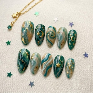 May include: A set of ten press-on nails featuring a marbled emerald green and white design with gold foil accents and raised gold celestial motifs including moons and stars, accompanied by a delicate gold chain necklace with a star charm.